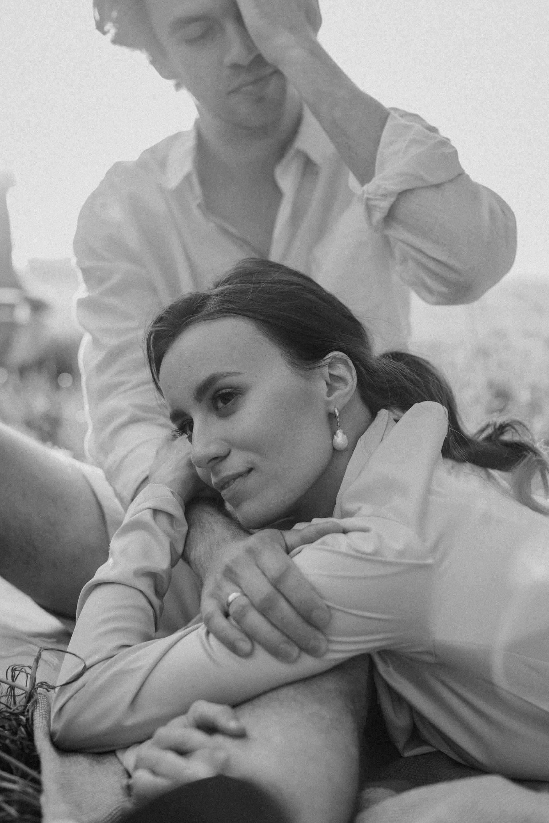 Wedding Website Design, Digital Wedding Stationery, Web Design and Branding for Wedding Professionals | Avelã White. Black and white photo of a woman resting her head on a man's arm, outdoors.